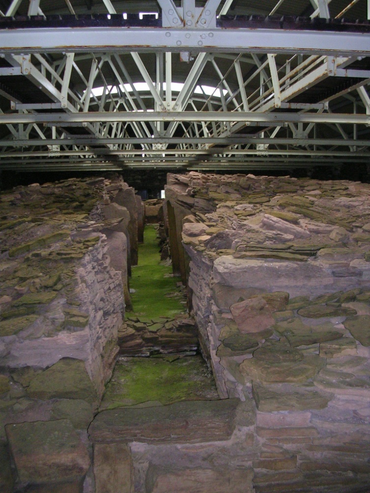 Inside the tomb of Midhowe with the long central passage and the metal struts of the roof which protects it