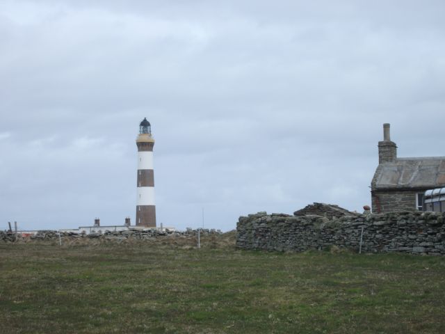 The striped lighthouse in North Ronaldsay with a house nearby