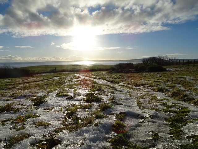 sun rising over a furrowed landscape with snow in the furrows