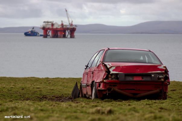 Scapa Flow with redundant platform and a disused abandoned car on the shore