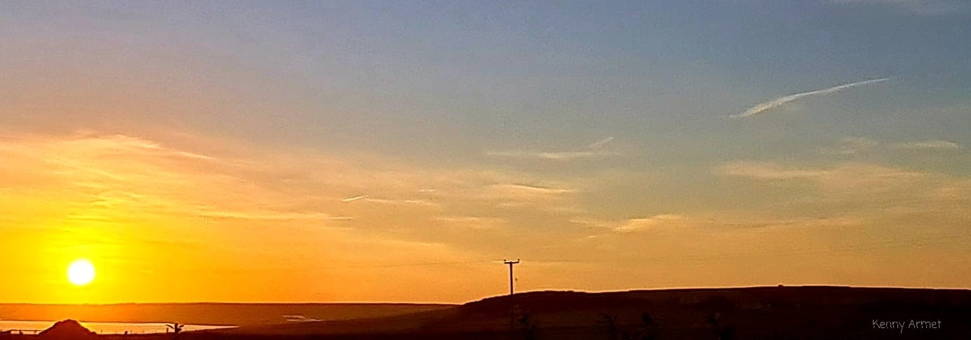 the rising sun over Orkney with a power line in the sky