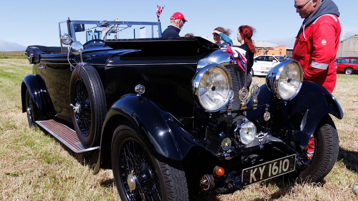 man standing looking at a vintage car