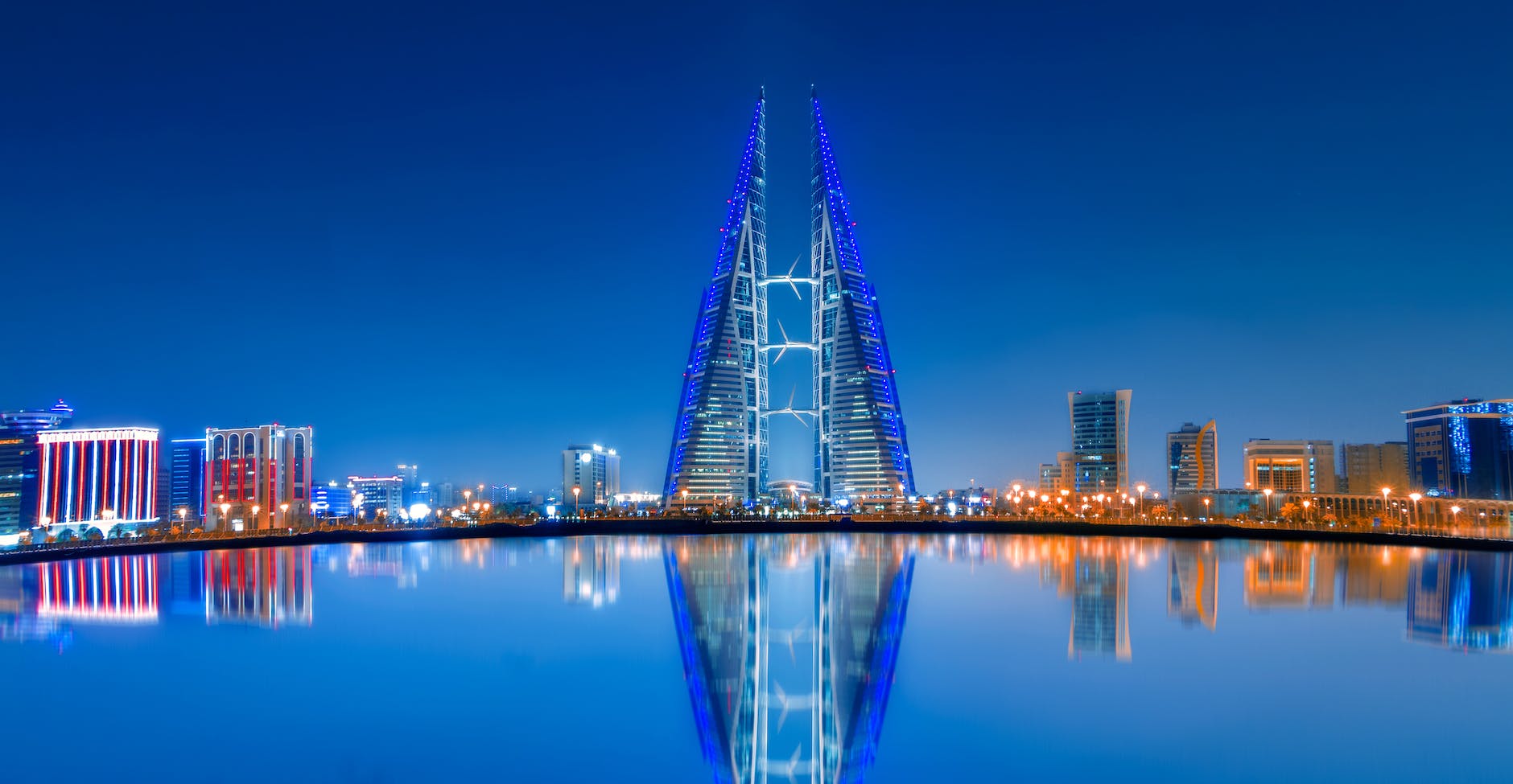 blue and purple lighted tower near body of water during night time