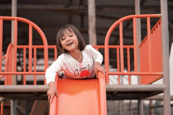 girl in white long sleeve shirt playing on a slide