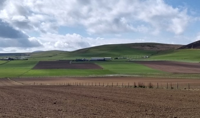 in front the recently ploughed and raked field and behind the green fields ready for grazing and the low hills over Yesnaby