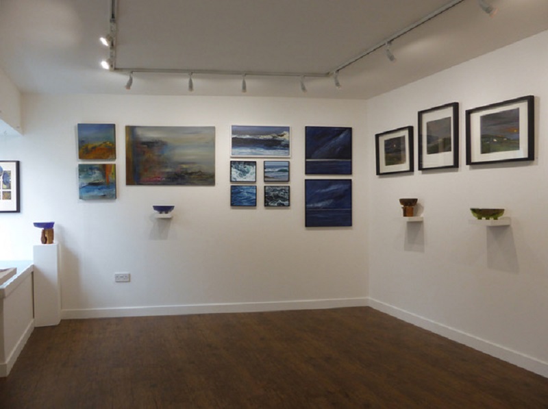 view inside the gallery space of paintings and pottery