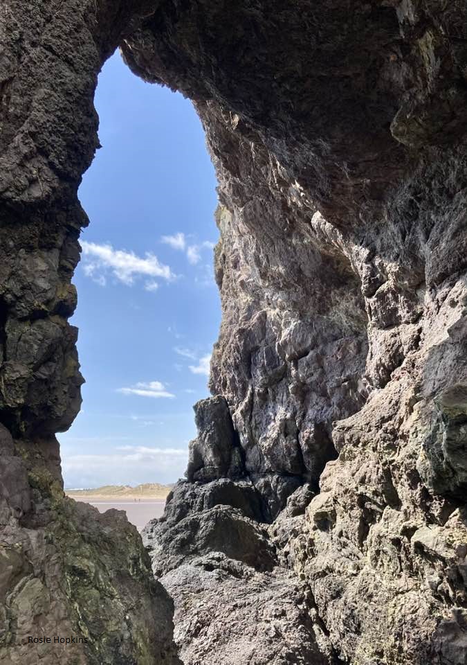 looking out from a cave entrance towards the sea, along the stretch of sand