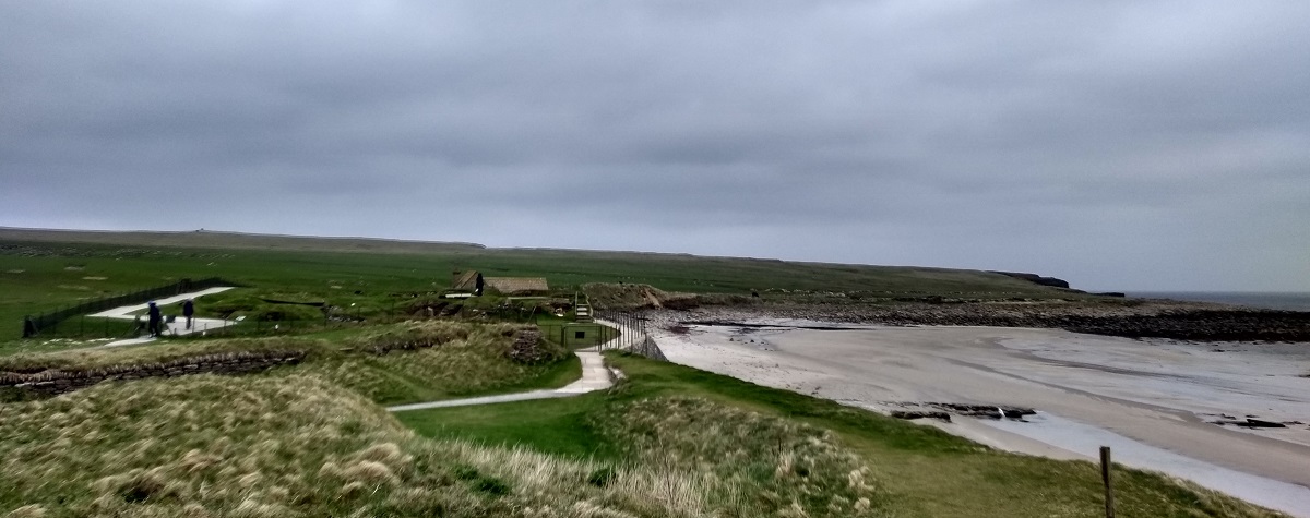 the neolithic village of Skara Brae with the sands of the Bay of Skaill