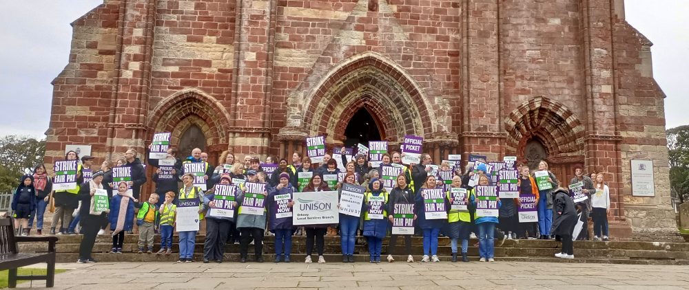 school staff with placards outside St Magnus Cathedral