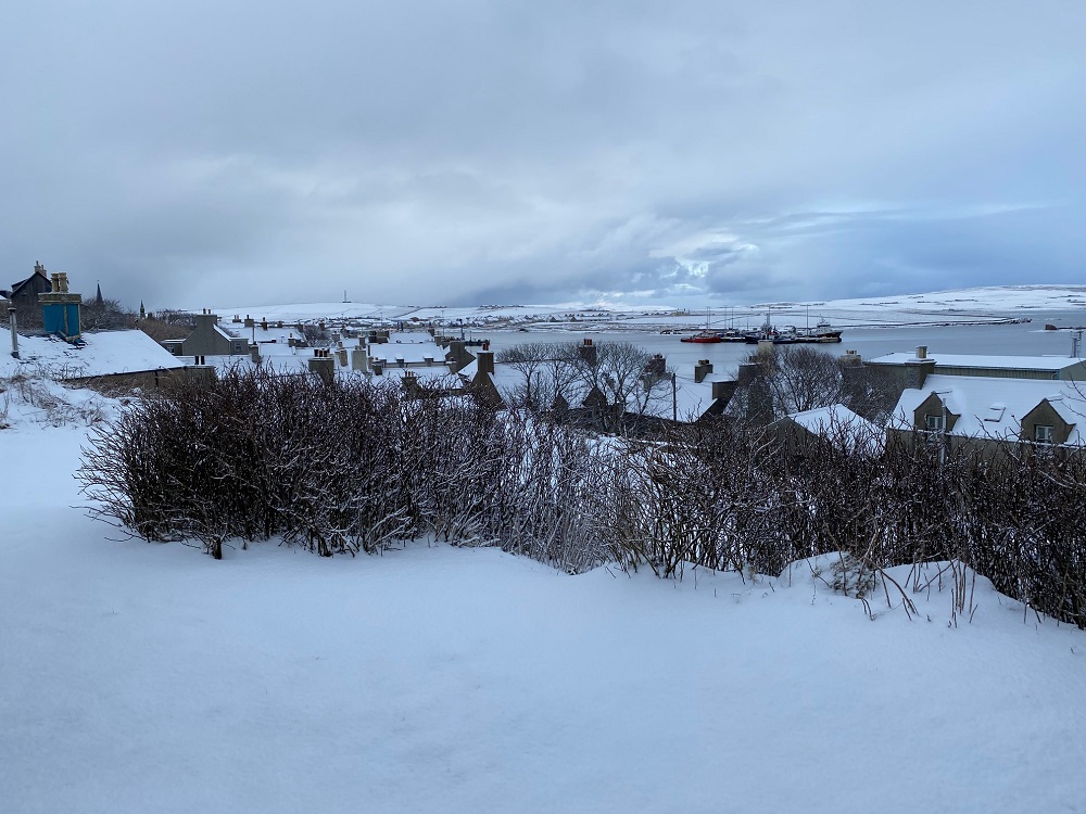 deep snow and the roof tops of Stromness view across a garden