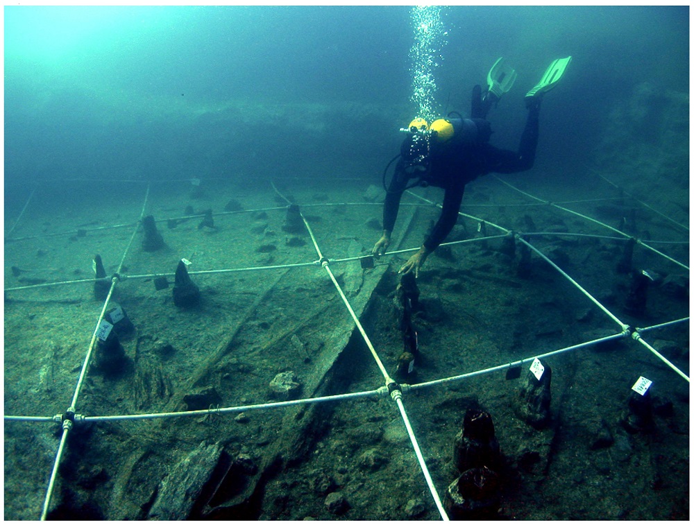a diver and the pegged off excavation site under water of the Neolithic canoe