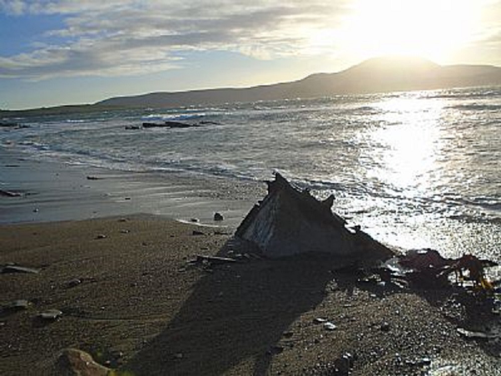 partly protruding from the sand the remains of some boat wreckage