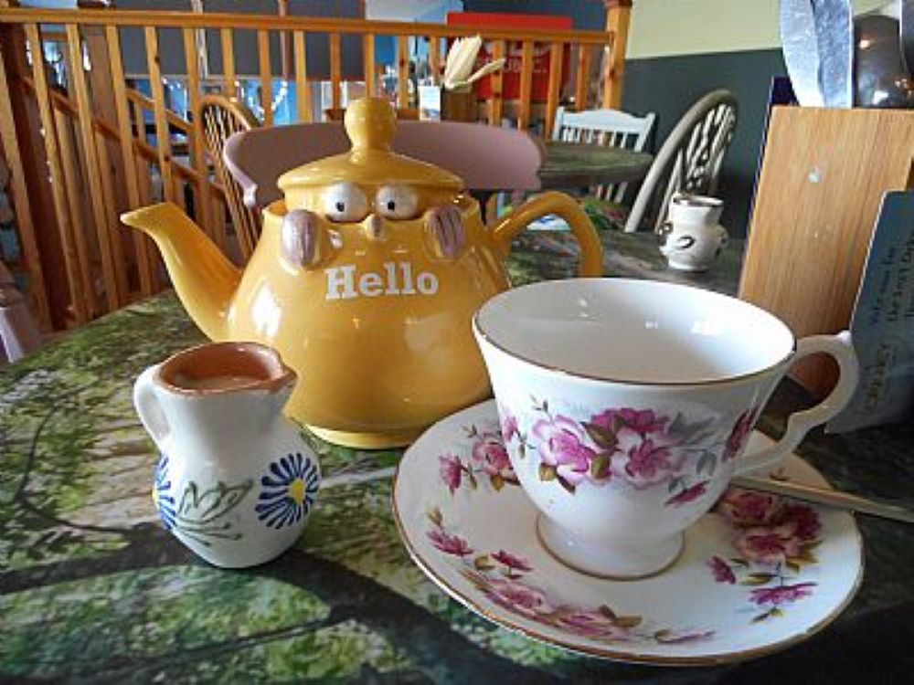tea cup and saucer little milk jug and a tea pot with a pair of eyes on its saying hello