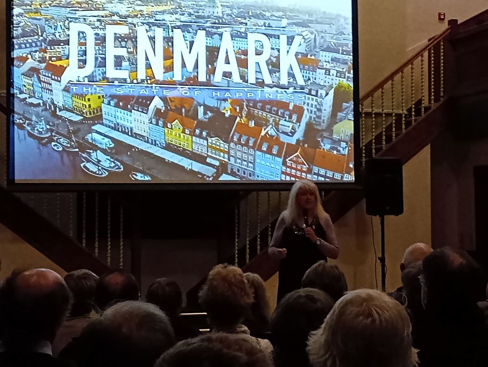 the screen showing the first image of the film, Denmark The State of Happiness, standing in front is Lesley Riddoch