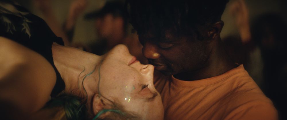 white woman lying back in the arms of a young black man