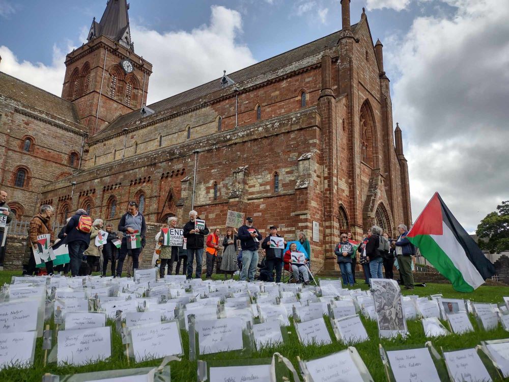 The Cathedral in the background and in front are those attending the vigil and the names of those killed