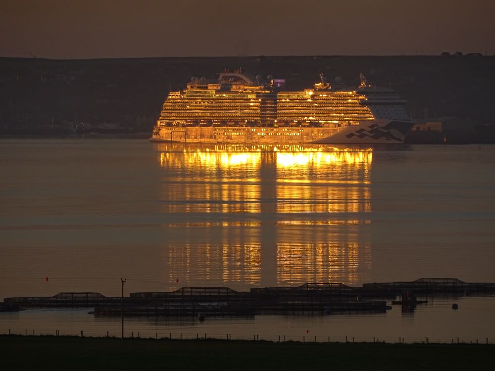 a liner all lit up aglow and reflected in the still waters of the Bay