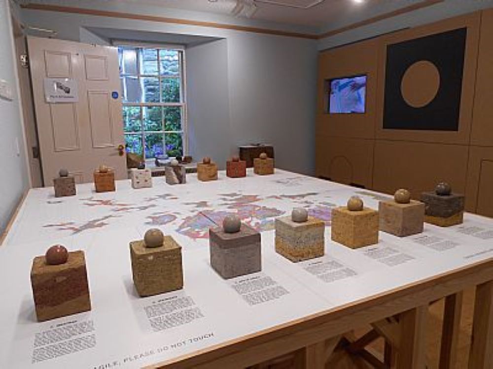a large table in the centre a map showing geological areas and at the top and bottom of the table cubes with clay balls on top showing the different layers of soil found in those areas