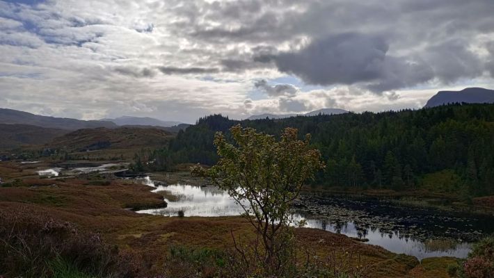 a U shaped valley with a river through it surrounded by hills outside of Ullapool in Scotland