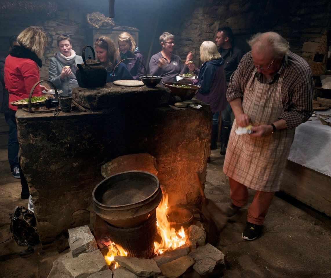 Andrew Appleby demonstrating how pots would be used for cooking in a Neolithic House with an open file in the grate