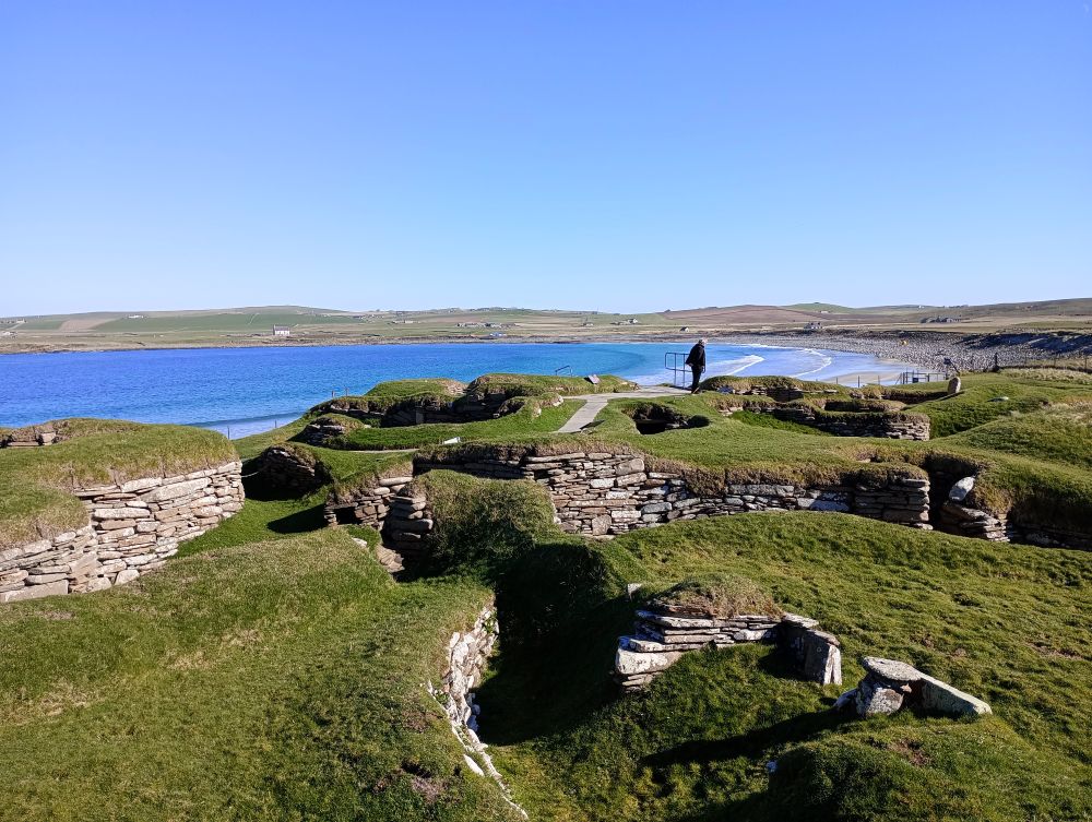a view across the Neolithic houses at Skara Brae with them half buried in the sand dune