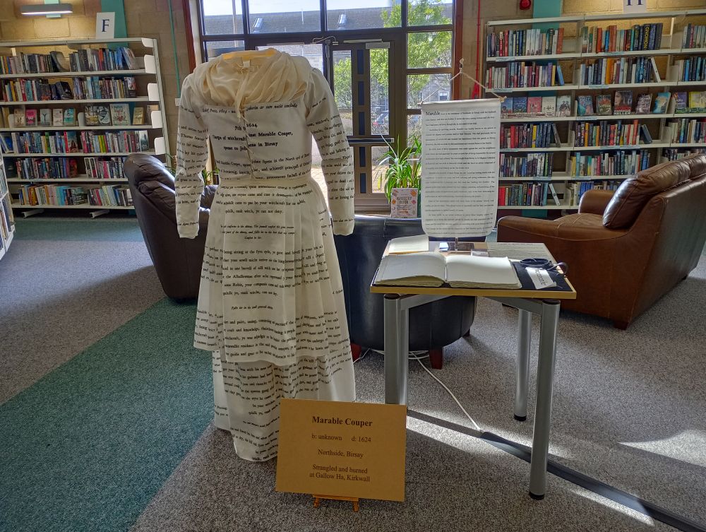the full length of the dress with the words printed across it and the other information on a desk beside it