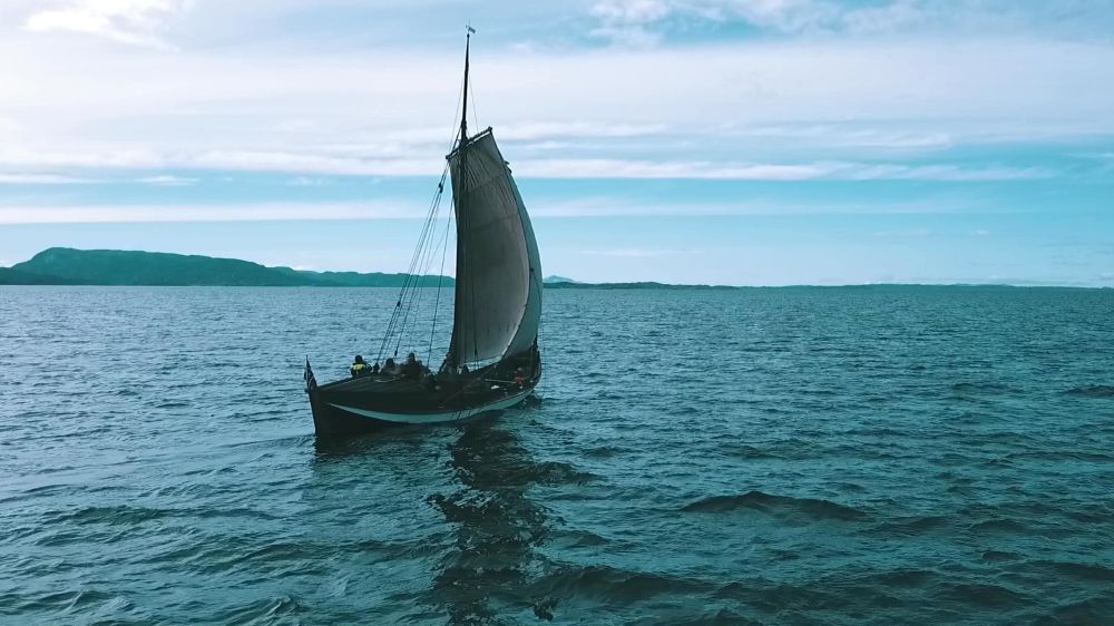 a long square sailed small boat out at sea