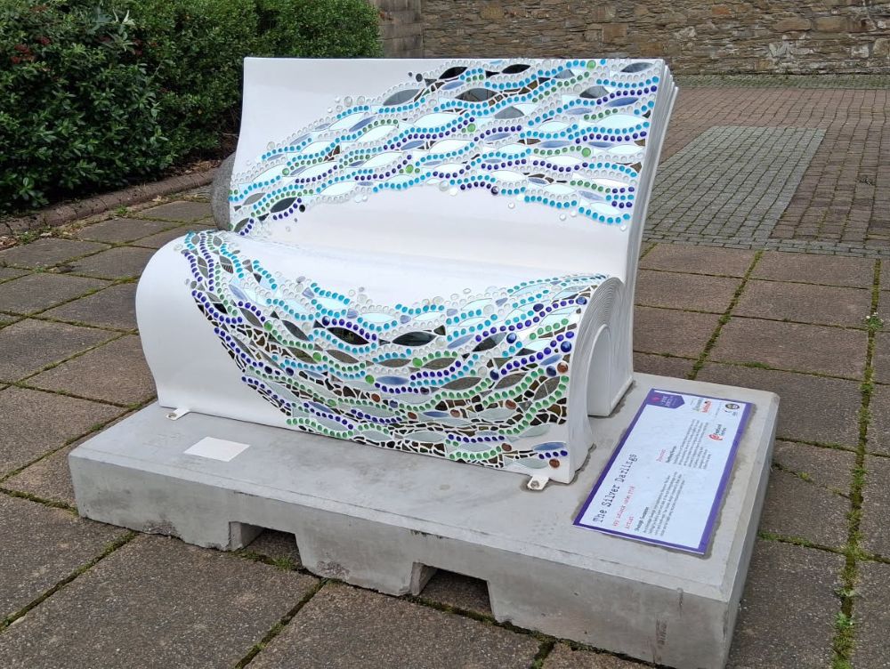 a white bench with shoals of fish across it and made up like the leaves of a book