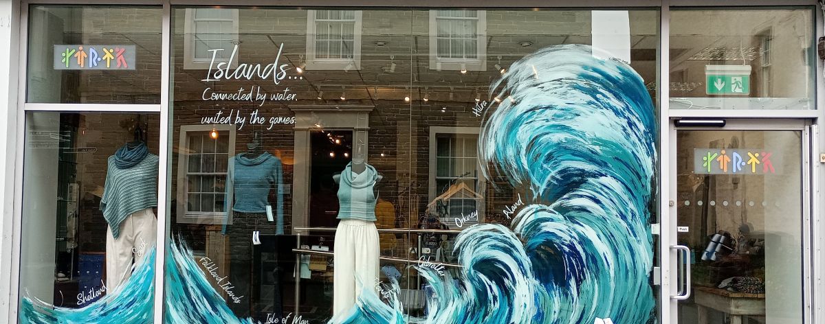 the shops window display for the Island Games for Hume Sweet Hume with large waves curving over and the names of the islands