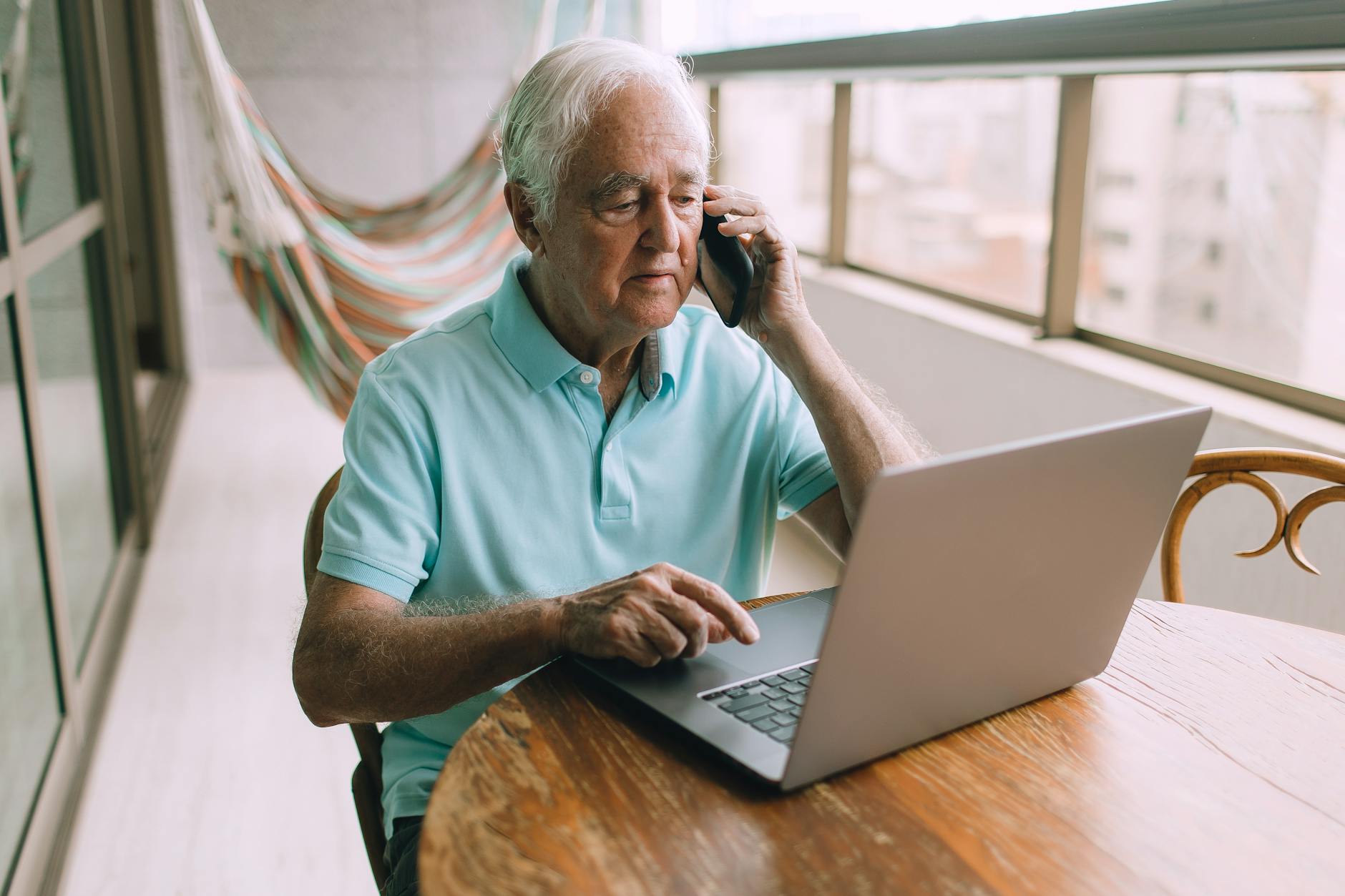 an elderly man with a laptop and a smartphone