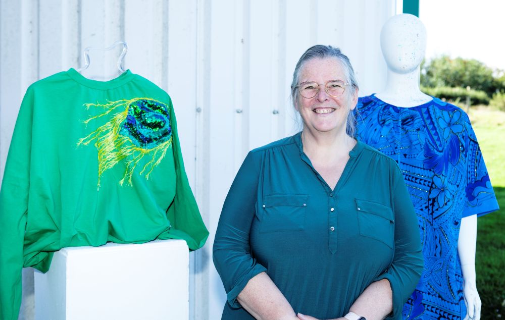 a smiling Briony beside some of her colourful designs