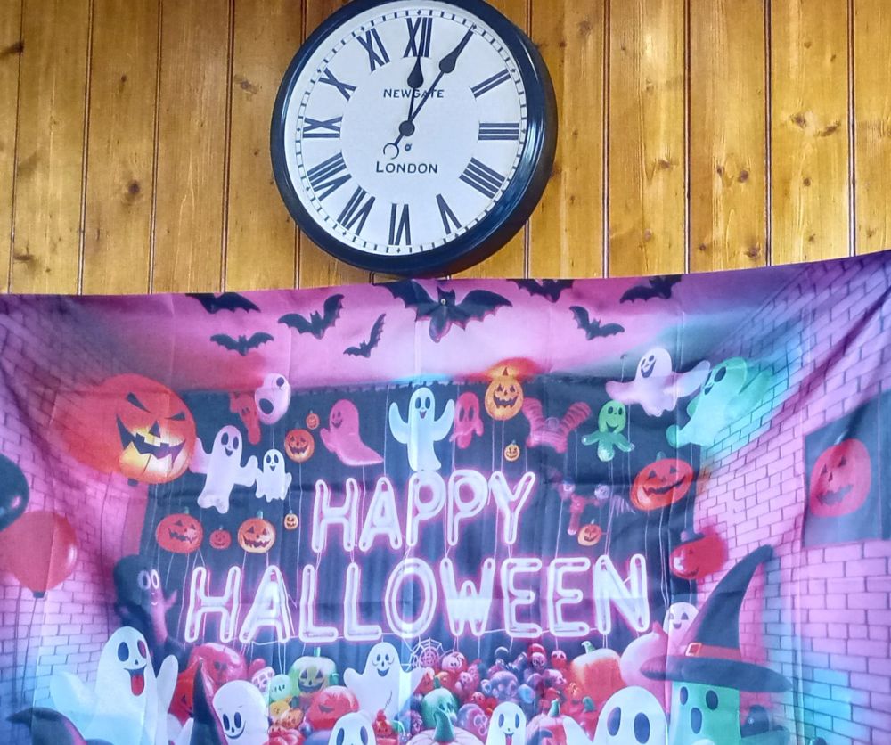 a clock on the wall with a Happy Halloween poster below it